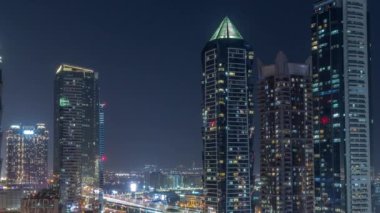 Modern mimari zaman çizelgesine sahip Business Bay semti ufuk çizgisi tüm gece boyunca yukarıdan devam edecek. Dubai gökdelenlerinin göz kırpan pencereleri ve ana karayolu yakınlarındaki aydınlatma kuleleri.