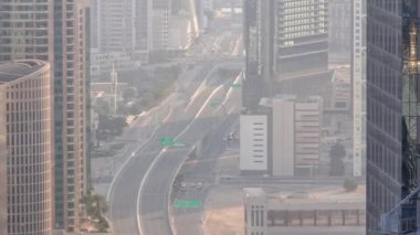 Şehir merkezindeki Dubai kavşağındaki yoğun yol kavşağına yukarıdan hava görüntüsü. Arabalar ve kamyonlar gökdelenler arasındaki yoldan her iki yöne doğru ilerliyor. Sisli hava