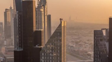 Dubai 'deki Sheikh Zayed Yolu' ndaki yüksek binalar. Gün batımında uluslararası finans bölgesinde gökdelenler. Arka planda evler ve villalar var. Turuncu ışık