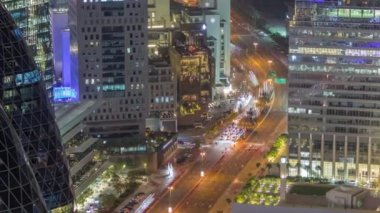 Al Saada caddesindeki trafiğin hava görüntüsü. Dubai, BAE 'deki finans bölgesi gece zaman çizelgesi. Aydınlatılmış gökdelenler ve yukarıdaki ofis kulelerinde parlayan pencereler.