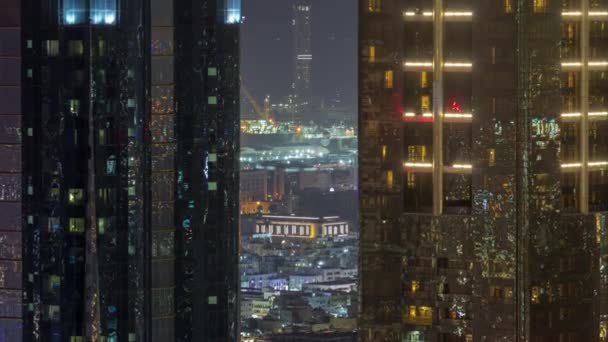 ダウンタウンの夜のタイムラプス近くにドバイ市内のアパートやヴィラに2つの高層ビルの間の空中ビュー 遠くに海港のライトアップされたクレーン アラブ首長国連邦 — ストック動画