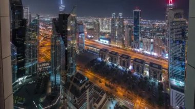 Dubai 'deki Sheikh Zayed Yolu' ndaki yüksek binalarda gece panoramik zaman dilimi, BAE. Uluslararası finans bölgesindeki gökdelenler. Arka planda evler ve villalar var.