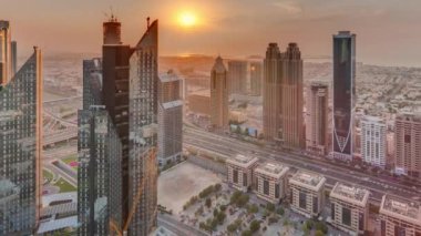 Dubai 'deki Sheikh Zayed Yolu' ndaki yüksek binalarda panoramik zaman dilimi, BAE. Gün batımında uluslararası finans bölgesinde gökdelenler. Arka planda evler ve villalar var.