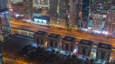 Dubai 'deki Sheikh Zayed Yolu' ndaki yüksek binalar gece uçuşları, BAE. Uluslararası finans bölgesindeki gökdelenler. Arka planda şehir yürüyüş evleri. Otoyolun yanındaki otopark.
