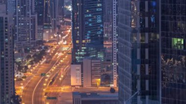 Hava görüntüsü Dubai 'deki yoğun kavşaklara gece gündüz geçiş zamanı. Gün doğmadan önce otoyolun her iki tarafına doğru giden arabalar var. İş bölgesi gökdelenleri