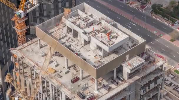 モノリシックオフィス高層ビルの新高層ビルの建設現場で働くタワークレーン高層ビルの空中時間経過 ドバイ金融地区の建設進捗状況 — ストック動画