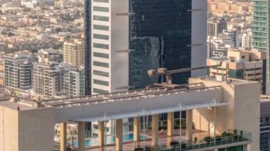 Dubai 'deki Sheikh Zayed Yolu yakınlarındaki gökdelenin tepesindeki çatı yüzme havuzu, BAE. Yukarıdan Uluslararası Finans Merkezi 'nde kuleler ve akşamları arkasında villalar.