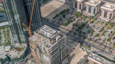 Dubai 'deki Sheikh Zayed Yolu' ndaki vinçleri ve binaları olan inşaat alanı. Finans bölgesinde gökdelenler, hareket eden uzun gölgeler. Bir sürü arabası olan park yeri.