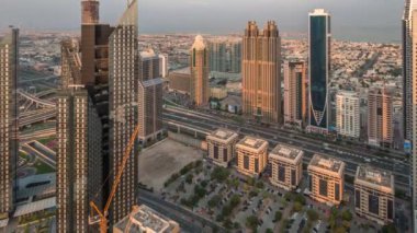 Dubai 'deki Sheikh Zayed Yolu' ndaki yüksek binalar sabah panoramik zaman dilimi, BAE. Güneş doğarken finans bölgesinde gökdelenler. Arka planda evler ve villalar var.