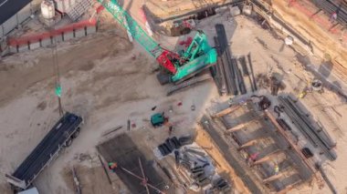 Yeni gökdelen zaman ayarlı bir temel çukuru olan hava manzaralı bir inşaat alanı. Toprak kazısı ve toprak dolumu. Vinç boşaltılırken toprak hareket etmek için ağır makineler.