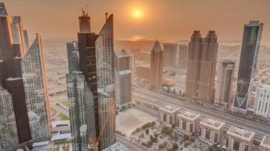 Dubai 'deki Sheikh Zayed Yolu' ndaki yüksek binalar. Gün batımında uluslararası finans bölgesinde gökdelenler. Arka planda evler ve villalar var. Turuncu gökyüzü