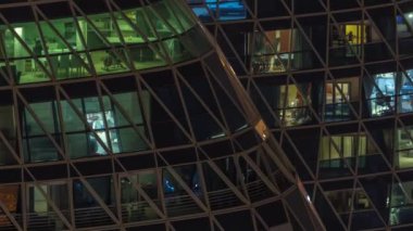 Kule binalarının ön cephesinden gece görüş açısı ve ışık zamanlaması olan bir sürü pencere. Her pencerede hayat var. Yerleşim yeri gökdelenlerinin cam cephesinin havadan görünüşü.