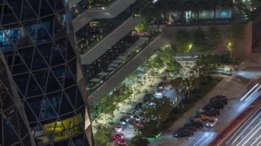 Gökdelenin açık hava terasındaki samimi restoranların gece zaman çizelgesine bakan hava manzarası. Dubai 'nin finans bölgesinde masalarda oturan insanlar. Otomobiller girişe yakın.