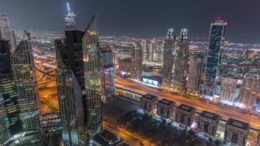 Dubai 'deki Sheikh Zayed Yolu' ndaki yüksek binalar gece uçuşları, BAE. Uluslararası finans bölgesindeki gökdelenler yukarıdan panoramik olarak görülüyorlar. Arka planda evler ve villalar var.