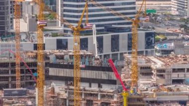 Çalışan vinçleri olan büyük bir inşaat alanı. Business Bay, Dubai 'deki büyük yerleşim ve ofis alanının en iyi hava görüntüsü. Takviyeli üniformalı işçiler
