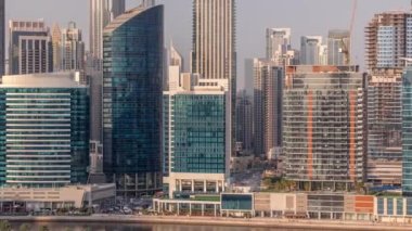 Dubai Business Bay ve Downtown 'ın havadan görüntüsü. Sahil boyunca çeşitli gökdelenler ve kuleler var. Kanal zamanlarında palmiyeler ve yeşil çimenler. Vinçli inşaat alanı