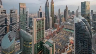 Sheikh Zayed Yolu 'ndaki yüksek binaların gökyüzü manzarası gece gündüz Dubai hava geçiş zamanı, BAE. Uluslararası Finans Merkezi 'ndeki gökdelenler güneş doğarken uzun gölgelerle tepeden görünüyor.