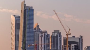 Dubai İşletme Koyu 'nun gökdelenleri ve su kanallarının zaman çizelgesi olan şehir manzarası. Günbatımında sıcak turuncu ışık altında konut ve ofis kuleleri olan modern gökyüzü.