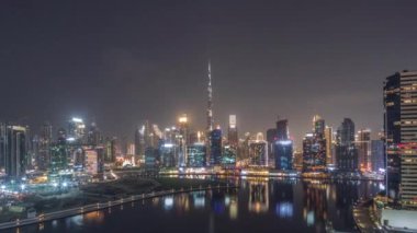 Hava panoramik görüntüsü Dubai Business Bay ve Downtown 'a tüm gece boyunca kanal boyunca çeşitli gökdelenler ve kuleler boyunca uzanır. Vinçli inşaat alanı