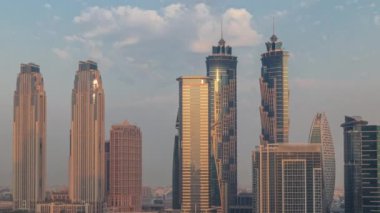 Dubai İşletme Koyu 'nun gökdelenleri ve su kanalı sabah saatleri ile şehir manzarası. Gündoğumunda konut ve ofis kuleleri olan modern gökyüzü. Güneş cam yüzeyden yansıyor