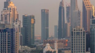 Dubai Business Bay hava sahasının gökdelenleriyle dolu şehir manzarası. Gündoğumunda mesken ve ofis kuleleriyle çevrili modern gökyüzü. Sıcak ışık ve uzun gölgeler