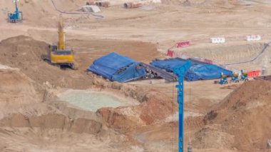 Apartman kompleksinin hava zaman ayarlı inşaatı için temel çukurunda yığın sürüşü. Kazı araçları, vinçler, buldozerler, Dubai gibi ağır makineler ile derin kurulum ve kazılar