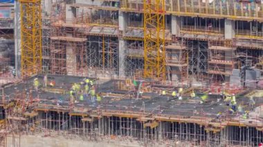 Çalışan vinçleri olan büyük bir inşaat alanı. Üniformalı ve kasklı işçiler. Business Bay, Dubai 'deki büyük yerleşim ve ofis alanının en iyi hava manzarası