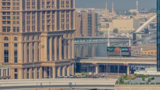 ドバイ航空タイムラプスのビジネスベイ地区の水上運河沿いの遊歩道を歩く ヴィラとモスクの後ろ 上から高層ビルでウォーターフロントに架かる橋 アラブ首長国連邦 — ストック動画