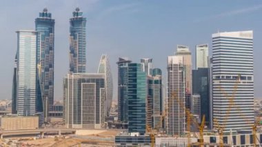 Dubai İşletme Koyu 'nun gökdelenleri ve su kanallarının zaman çizelgesi olan şehir manzarası. Konut ve ofis kuleleri olan modern gökyüzü. İnşaat alanında çalışan sarı turnalar