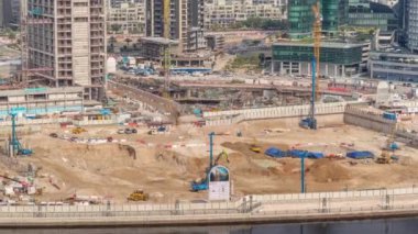 Apartman kompleksinin hava zaman ayarlı inşaatı için temel çukurunda yığın sürüşü. Kazı makineleri, vinçler, buldozerler ve kamyonlar olarak derin kurulum ve kazılar, Dubai
