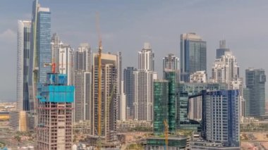 Dubai İşletme Koyu 'nun gökdelenleri ve su kanallarının zaman çizelgesi olan şehir manzarası. İnşaat alanında bir sürü vinç var. Rıhtım ve işyeri kuleleri olan modern gökyüzü.