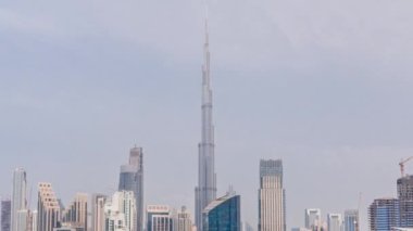 Dubai Business Bay ve şehir merkezinin havadan görüntüsü. Kanal zamanındaki çeşitli gökdelenler ve kuleler. Vinçleri olan bir inşaat alanı. Gün boyunca bulutlu gökyüzü