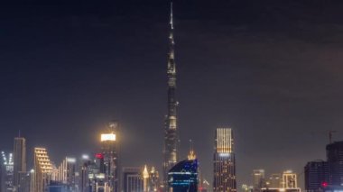 Tüm gece boyunca Dubai Business Bay ve Downtown 'ın havadan görüntüsü. Kanal boyunca çeşitli gökdelenler ve kuleler var. Vinçleri olan bir inşaat alanı. Bulutlar ve sis