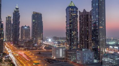 Günbatımından günbatımından sonra modern mimari zaman çizelgesine sahip Business Bay semti silüeti. Ana karayolu yakınlarındaki Dubai gökdelenlerinin ve kulelerinin havadan görüntüsü. Kavşakta trafik vardı.