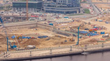 Apartman kompleksi zaman tüneli inşaatı için temel çukuru. Kazı makinesi, vinç, buldozer, beton karıştırıcı ve kamyon gibi ağır makinelerle derin kurulum ve kazılar, Dubai