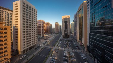 İkamet binaları ve Abu Dabi hava saatinin modern şehir mimarisi tüm gece boyunca gün doğumuna kadar, BAE. Otoparkta yukarıdan arabalara ve gökdelenli kulelerin uzun gölgelerine bak