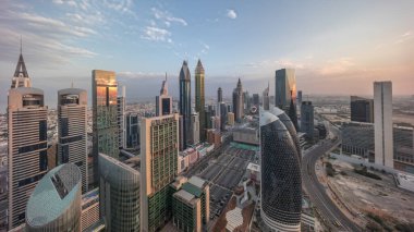 Güneşin doğuşundan batışına kadar tüm gün boyunca Dubai 'deki Sheikh Zayed Yolu' ndaki gökdelenlerin panoramik görüntüsü. Yukarıdan Uluslararası Finans Merkezindeki Gökdelenler