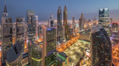 Sheikh Zayed Yolu 'ndaki yüksek binaların gökyüzü manzarası gece gündüz Dubai hava geçiş zamanı, BAE. Uluslararası Finans Merkezi 'ndeki gökdelenler güneş doğarken uzun gölgelerle tepeden görünüyor.