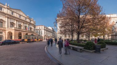 Panorama showing theater La Scala timelapse and a small park opposite to historic building with a monument to Leonardo da Vinci and his students. People walking around and sitting on a bench
