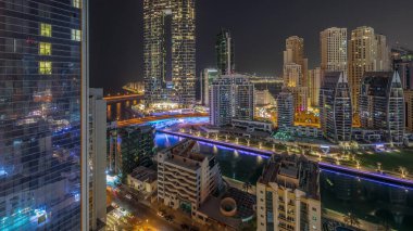 Dubai Marina gökdelenleri ve JBR semti. Lüks binalar ve otellerin zaman çizelgeleri var. Işıklar tüm gece kapalı. Aydınlatılmış rıhtım ve kanalda yüzen tekneler