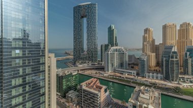 Panorama, Dubai Marina 'yı limana parkedilmiş tekne ve yatlarla ve kanalın çevresindeki gökdelenlerle gün doğumunda hava durumunu gösteriyor. Arka planda JBR bölgesi kuleleri