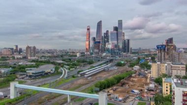 Moskova gökdelenlerinin iş kompleksi hava panorama günden geceye geçiş zamanı. Ön planda demiryolu ve otomobil üst geçidi. Bulutlu gökyüzü ve gün batımından sonra çatıdan gelen trafik