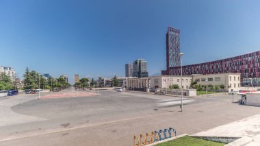 Panorama, Tiran 'daki Deshmoret e Kombit Bulvarı' nda trafiği gösteriyor. Arnavutluk başkentinin ana caddesi yeşil ağaçlar ve gökdelenlerle çevrili. Üniversitenin yakınındaki meydanda arabalar hareket ediyor