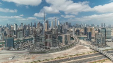 Panorama Dubai 'nin ufuk çizgisini iş sahası ve şehir merkezi zaman çizelgesiyle gösteriyor. Bulutlu mavi gökyüzü olan birçok modern gökdelenin havadan görünüşü. Birleşik Arap Emirlikleri.