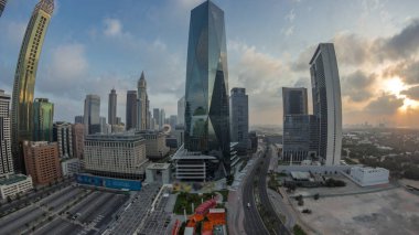 Dubai Uluslararası Finans Bölgesi 'nin gece gündüz geçiş panoraması. Gün doğumunda iş yerinin hava manzaralı kuleleri. Şehir merkezine yakın oteller ve alışveriş merkezleriyle aydınlatılmış gökdelenler.