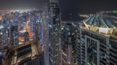 Panorama, Dubai Marina 'yı JLT ve JBR bölgesiyle gösteriyor. Gökdelenler arasındaki otoyolda trafik vardı. Hava gece zaman çizelgesi. Aydınlatılmış modern kuleler ve inşaat alanı