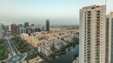 Barsha Heights bölgesindeki gökdelenleri ve Yeşiller bölgesindeki alçak binaları gösteren panorama. Palmiyeler ve ağaçlarla Dubai silueti