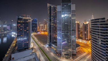 Panorama Dubai Business Bay 'deki gökdelenleri gösteriyor. Su kanalı gece zaman ayarlı. Aydınlatılmış kuleleri ve rıhtımı olan modern gökyüzü. Uluslararası bir iş merkezi.