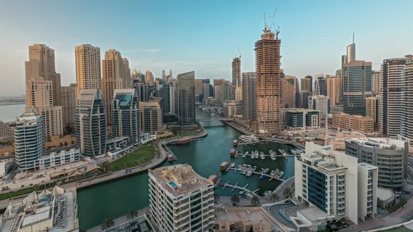 Panorama showing Dubai Marina skyscrapers and JBR district with luxury buildings and resorts aerial timelapse. Waterfront with palms and boats floating in canal