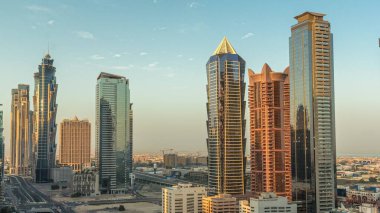 Business Bay semtinin ufuk çizgisi modern mimari ile sabah saatleri yukarıdan geliyor. Güneş doğarken Dubai gökdelenlerinin ve ana karayolu yakınlarındaki kulelerin havadan görüntüsü. Yol ayrımında trafik ve uzun gölgeler